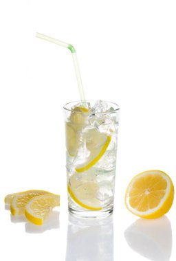 Beyaz zemin üzerinde limon ve buz olan bir bardak su.