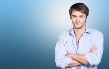 Mavi arka planda duran zeki, gülümseyen genç bir adamın portresi.