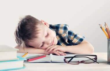Yorgun çocuk masada oturuyor ve uyuyor.