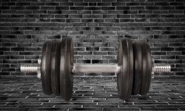 Siyah halterin ağırlığı siyah tuğla taşın üzerinde.