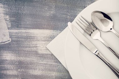 Ahşap zemin üzerinde bıçak, kaşık ve çatal olan boş tabak.