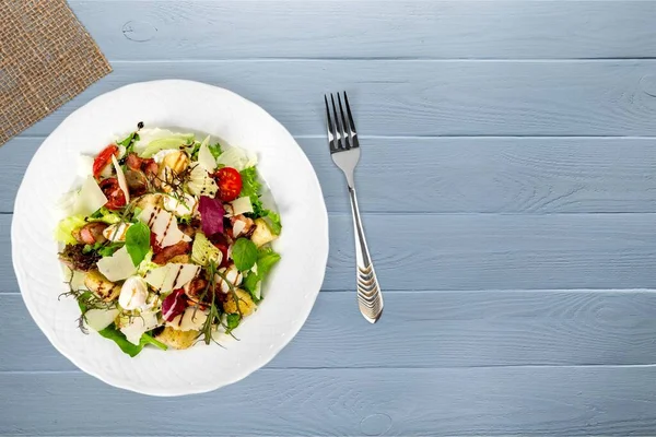 Taze sebzeli salata ve ahşap arka planda fındık.