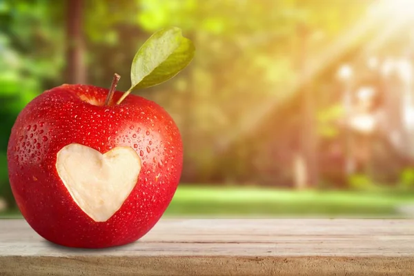 Red apple with a heart shaped cut-out on background