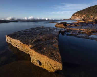 Bouddi Ulusal Parkı 'ndaki sahil şeridindeki kayalara su sıçrıyor. 
