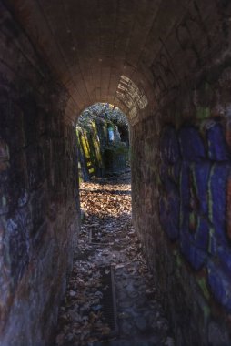 Sonbaharda tünelin sonundaki duvar yazıları ve ışıklarla dolu tünel dar taş geçit.