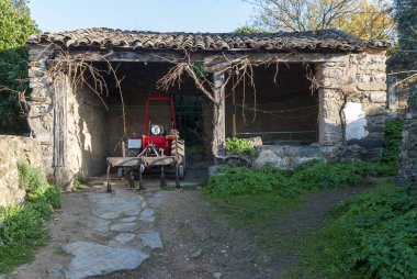 Taştan, ahşaptan ve fayanslardan yapılmış garaja park edilmiş tarımı için kırmızı tarımsal traktör