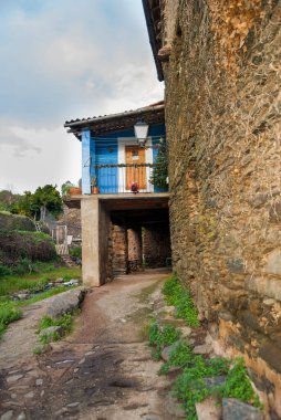 Robledillo de Gata 'nın tipik kırsal mimarisi, kayrak ev ve yakınlardaki bir dere kenarındaki meyve bahçesi.