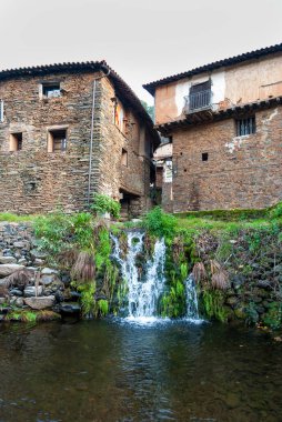Robledillo de Gata 'nın tipik kır mimarisi, küçük şelale, kayrak ev ve çam ormanı arka planda dikey
