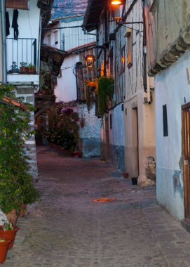 Akşam karanlığında Hervas 'ın Yahudi mahallesinin caddesi, çömleklerle ve taş zeminle kaplı sokak.