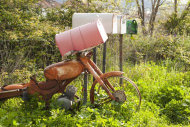 recycled retro mailboxes with old rusty vintage motorcycle in the countryside