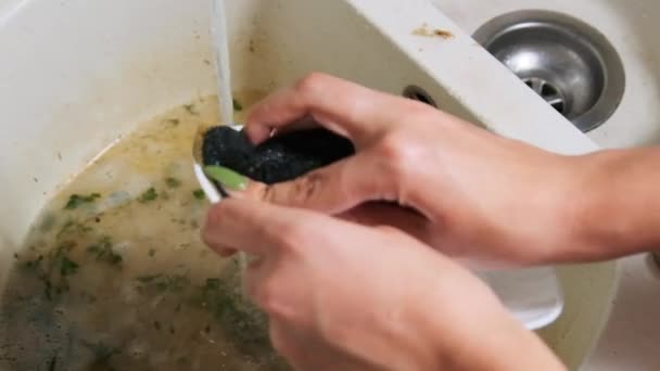 Jovem mulher lava os pratos na pia suja na cozinha em casa, câmera lenta — Vídeo de Stock