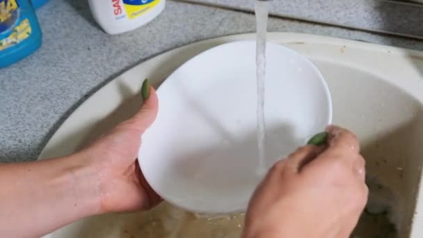 Mladá žena myje nádobí ve špinavém umyvadle v domácí kuchyni, pomalý pohyb — Stock video