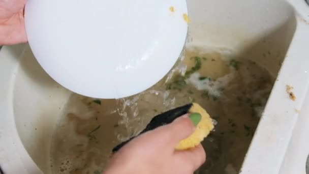 Jovem mulher lava os pratos na pia suja na cozinha em casa, câmera lenta — Vídeo de Stock