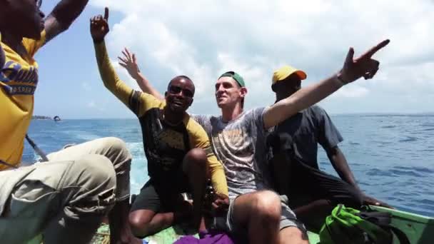 Joyeux touriste blanc avec des Africains chante une chanson se déplaçant sur un vieux bateau dans l'océan — Video