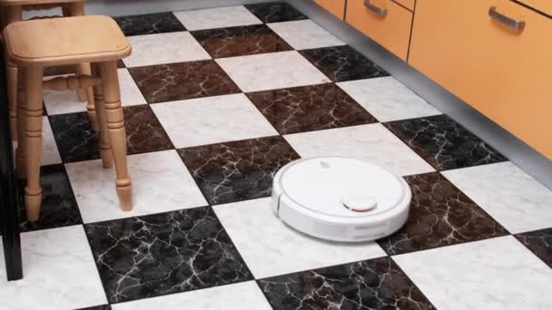 Robot aspiradora limpia en la casa moderna en el piso de la cocina — Vídeos de Stock