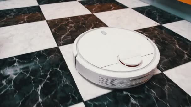La aspiradora Robot limpia en la casa moderna en el piso de baldosas en la cocina — Vídeo de stock