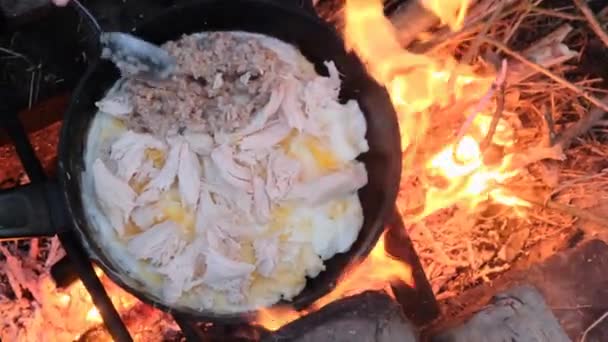 Vaření vejce s kuřecím masem, ovesná kaše na turistickém táboře pánev smažení, příroda — Stock video