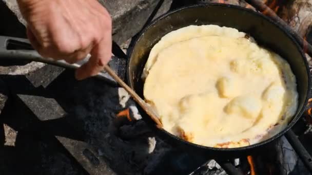 Cuisiner une omelette sur un feu de camp dans une poêle à frire touristique dans la nature — Video