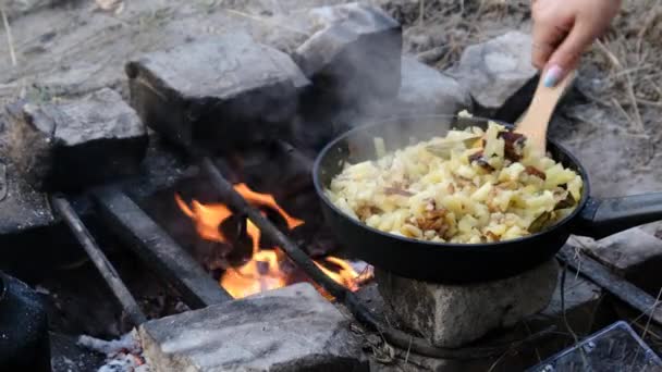 Gefrituurde aardappelen koken in koekenpan boven een vuurhaard op zelfgemaakte kachel — Stockvideo