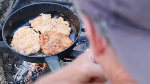 Homme cuisson côtelettes de porc frites dans l'huile dans la poêle sur le feu extérieur, Viande grasse — Video