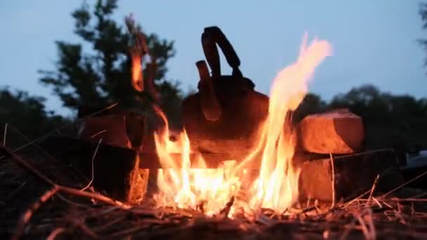 Alter Touristenkessel steht in der Dämmerung mit Flammen am Lagerfeuer — Stockvideo