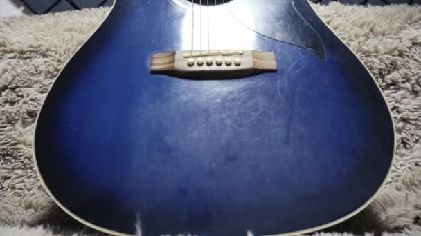 Ακουστική κιθάρα βρίσκεται σε έναν καναπέ μέσα σε ένα δωμάτιο με εσωτερικό — Αρχείο Βίντεο