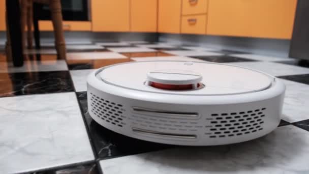 Der Staubsaugerroboter reinigt im modernen Haus auf dem Fliesenboden in der Küche