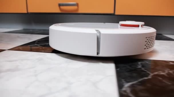 Το ρομπότ ηλεκτρική σκούπα καθαρίζει στο σύγχρονο σπίτι στο πάτωμα πλακάκια στην κουζίνα — Αρχείο Βίντεο