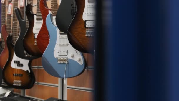 Lot of Multicolored Electric Guitars Hanging in a Music Store, Guitar Shop — Vídeo de Stock