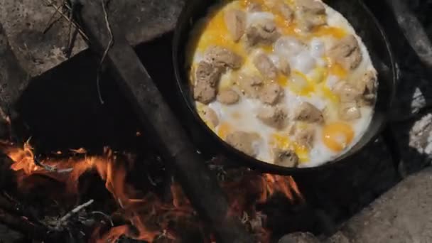 Cuisson oeufs brouillés avec de la viande de poulet sur feu de camp touristique poêle, nature — Video
