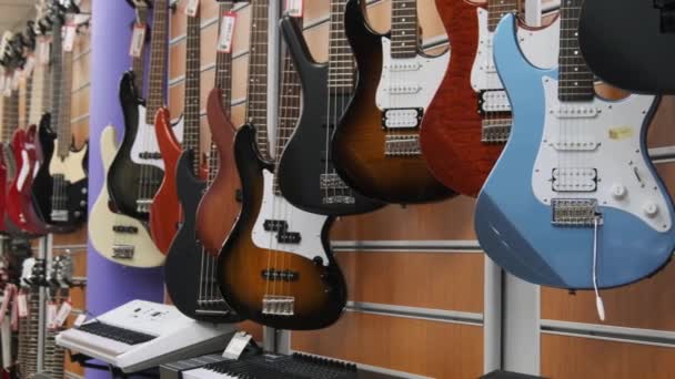 Lote de guitarras elétricas multicoloridas penduradas em uma loja de música, loja de guitarra — Vídeo de Stock