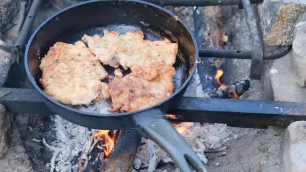 Άνδρας μαγείρεμα τηγανητά χοιρινά κομμάτια σε λάδι σε τηγάνι τηγανίσματος πάνω από τη φωτιά Εξωτερική, λίπος κρέας — Αρχείο Βίντεο