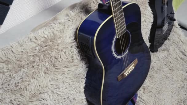 Las guitarras acústicas y eléctricas se encuentran en un sofá dentro de una habitación con un interior casero — Vídeos de Stock