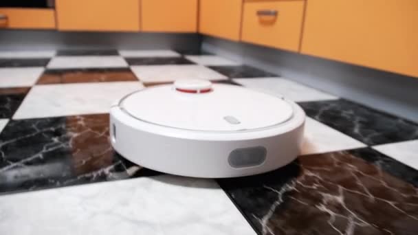 La aspiradora Robot limpia en la casa moderna en el piso de baldosas en la cocina — Vídeos de Stock