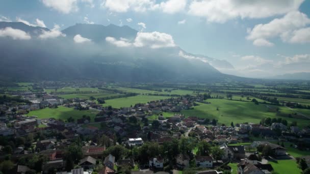 Vista aérea de Liechtenstein con casas en campos verdes en Alpes Mountain Valley — Vídeos de Stock