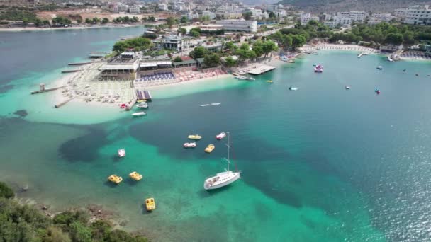 Aerial, Azure Beach with Empty Sun Loungers and Boats, Wybrzeże Morza Bałkańskiego, Albania — Wideo stockowe