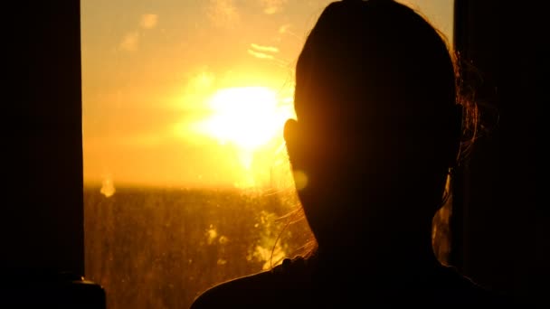 一个年轻女子在夕阳西下从窗户往外看的轮廓，动作缓慢 — 图库视频影像
