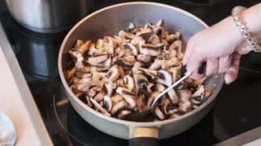 Mantarlar ev mutfağında bir tavada kızartılıyor, Julienne mantarları pişiriliyor.