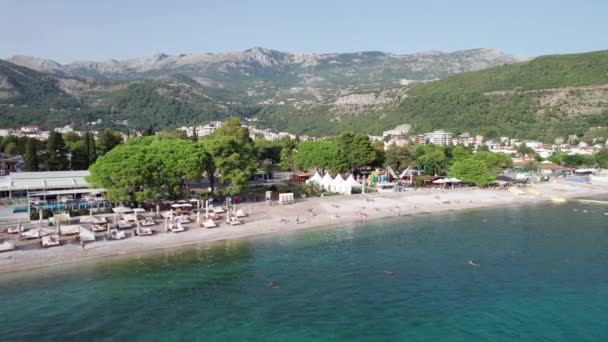 Vista aérea de la playa de Budva por mar con reposeras y gente, costa Montenegro — Vídeos de Stock