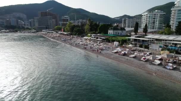 Vista aérea de la playa de Budva por mar con reposeras y gente, costa Montenegro — Vídeos de Stock