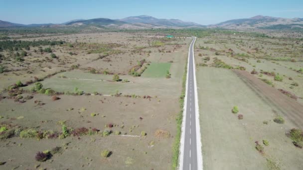 緑のフィールドの間の高原の空のアスファルト道路、ハイランドウェイ空中ビュー — ストック動画