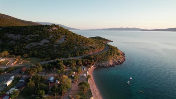 Widok z lotu ptaka na skaliste wybrzeże Chorwacji z zakręconą drogą o zachodzie słońca — Wideo stockowe