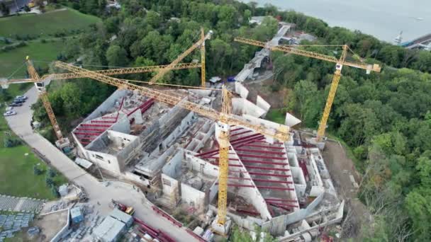 Vista aérea Construção de um novo edifício com guindastes de alta torre em área verde — Vídeo de Stock