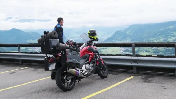 Cyklista na turistické motorce se zavazadlovými taškami Stands by Mountain Landscape, Alpy — Stock video