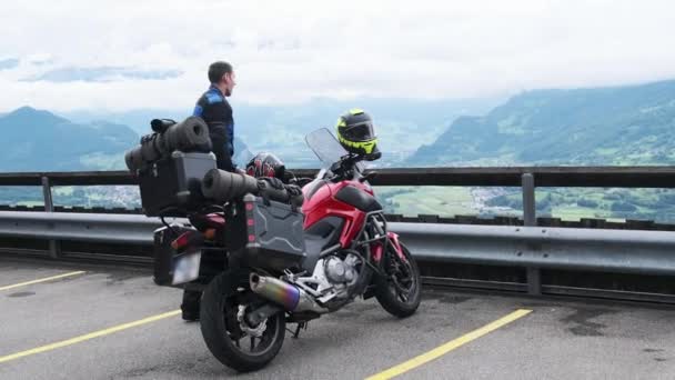 Cyklista na turistické motorce se zavazadlovými taškami Stands by Mountain Landscape, Alpy — Stock video