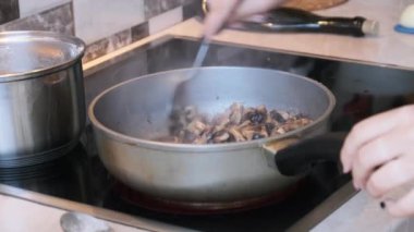Mantarlar ev mutfağında bir tavada kızartılıyor, Julienne mantarları pişiriliyor.