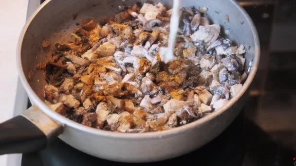 Aggiunta di crema di latte ai funghi fritti in una padella calda presso la cucina domestica. Julienne — Video Stock