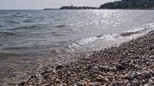 阳光明媚的日子，在卵石沙滩上平静的水边 — 图库视频影像