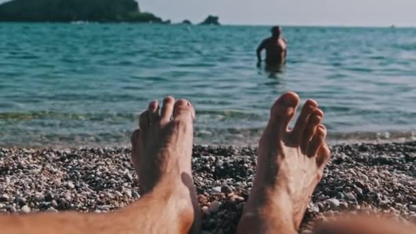 POV Joven hombre descalzo pies en la playa de guijarros por el paisaje marino — Vídeo de stock