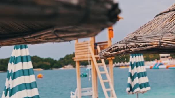 ローシーズン、アルバニア、 Ksamilの青い海の背景にあるストロービーチ傘 — ストック動画